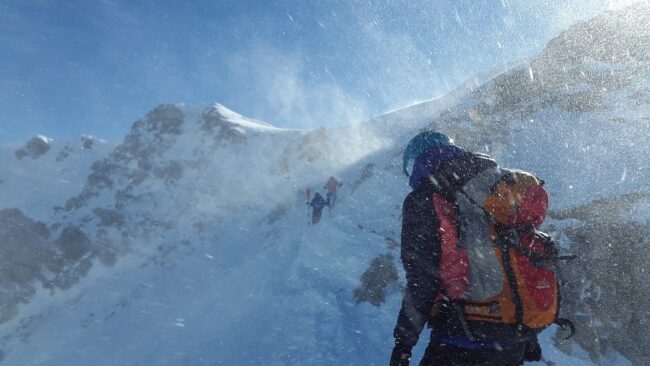 The man hiking up the mountain in heavy winter conditions. Strategy Execution is like planning a trip to the mountains. Realizacja strategii jest jak wyprawa w góry.